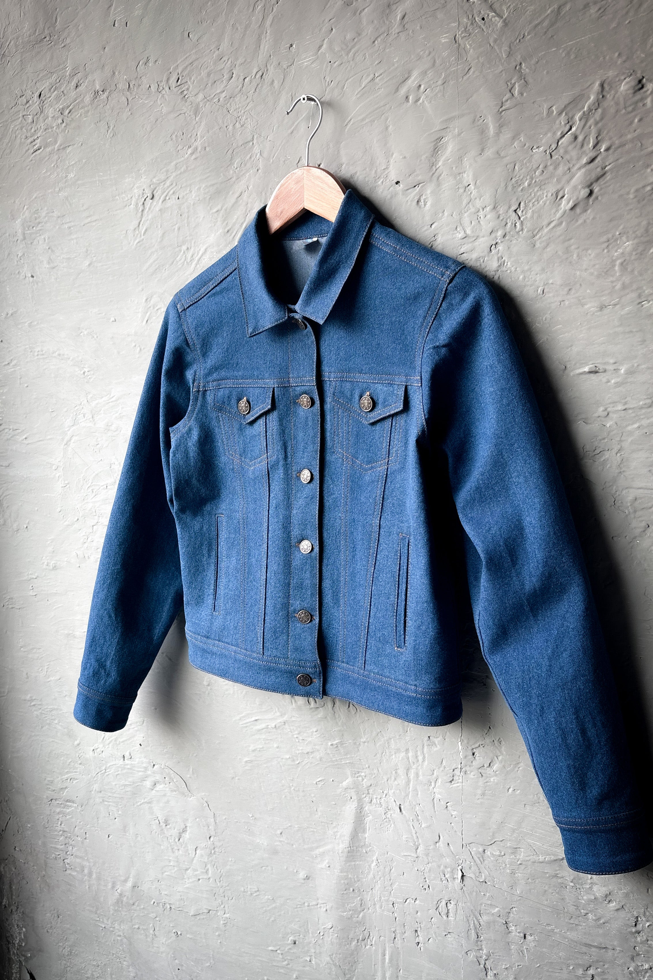 Blue denim jacket hanging on a gray textured wall